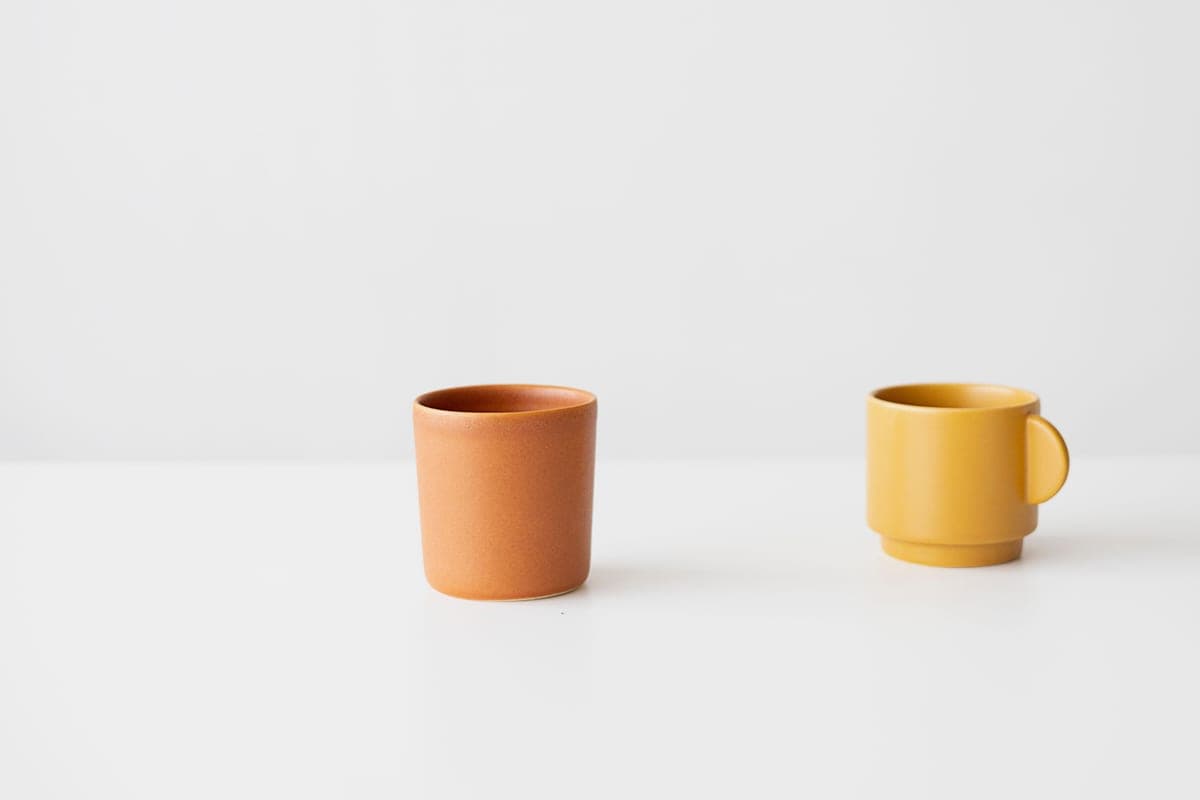 Two plain ceramic cups side by side on a white surface
