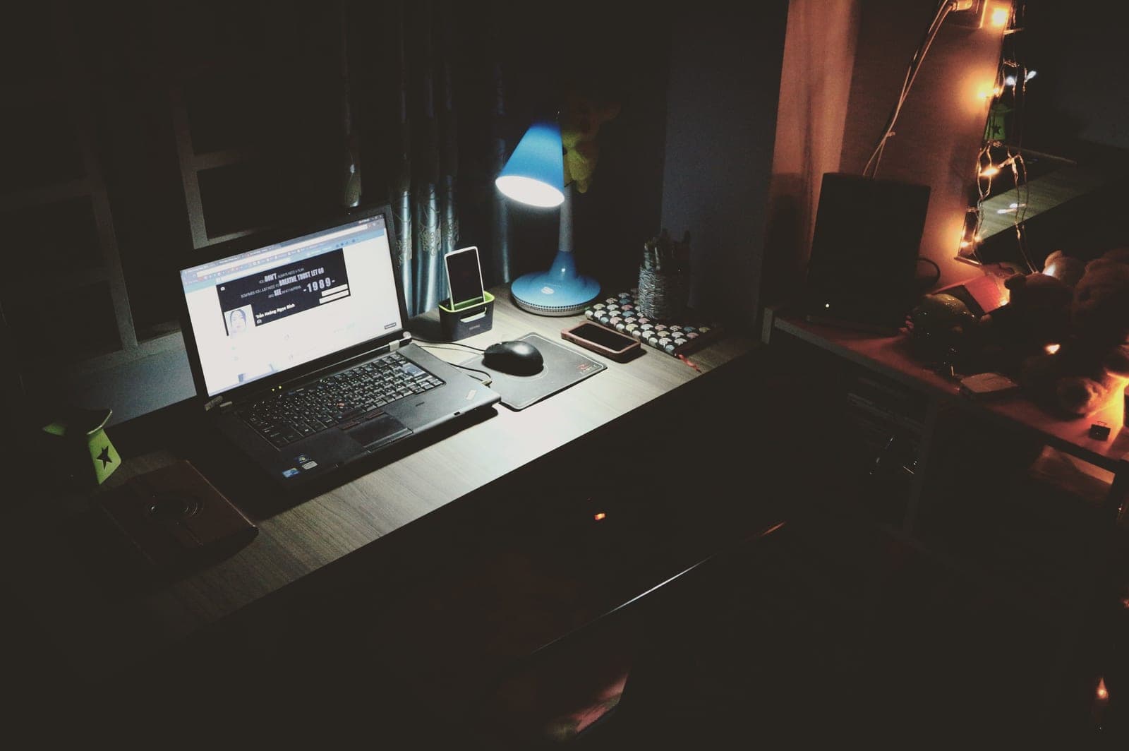 A desk lamp lighting a laptop and mouse in an otherwise dark room