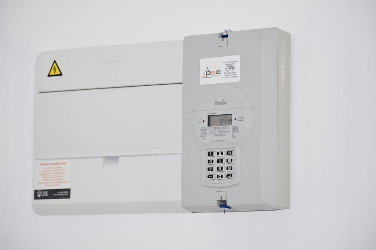A domestic electricity meter box mounted on a white wall