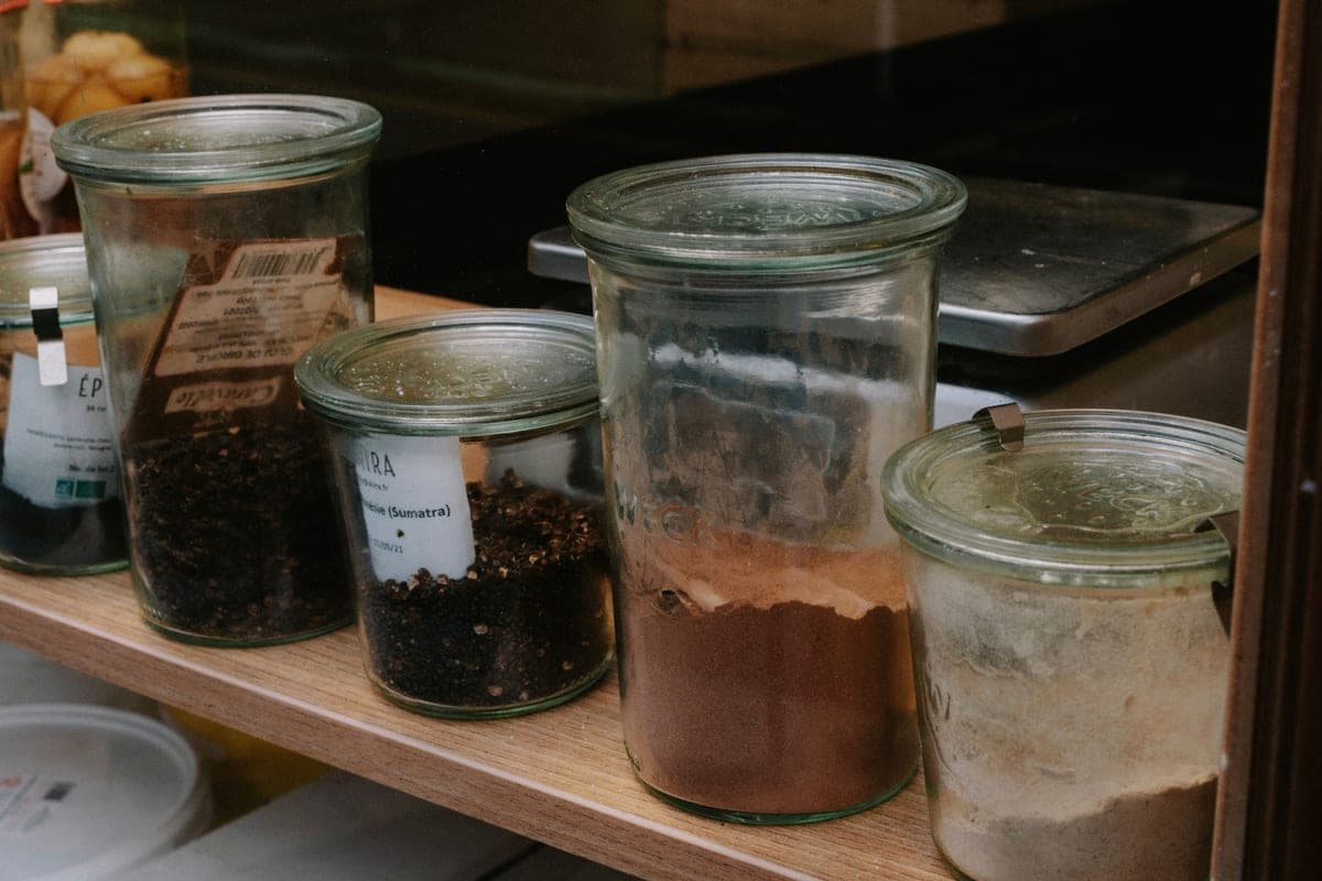 Rows of glass storage jars on a wooden pantry shelf